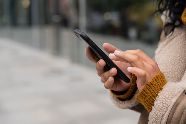 Mujer que usa su teléfono inteligente afuera con espacio de copia