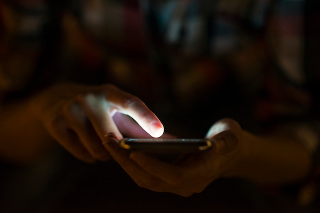 Mujer que usa su teléfono móvil, fondo de la luz de la noche del horizonte de la ciudad