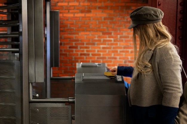 Foto gratuita mujer que usa una tarjeta de metro para viajar con el metro en la ciudad