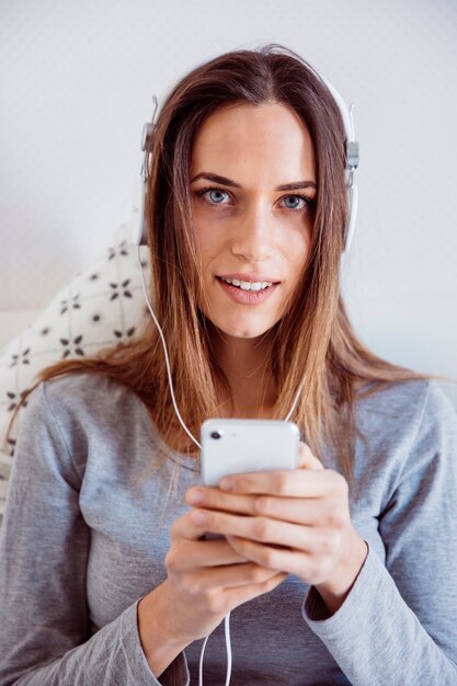 Mujer que usa el teléfono inteligente y escucha música