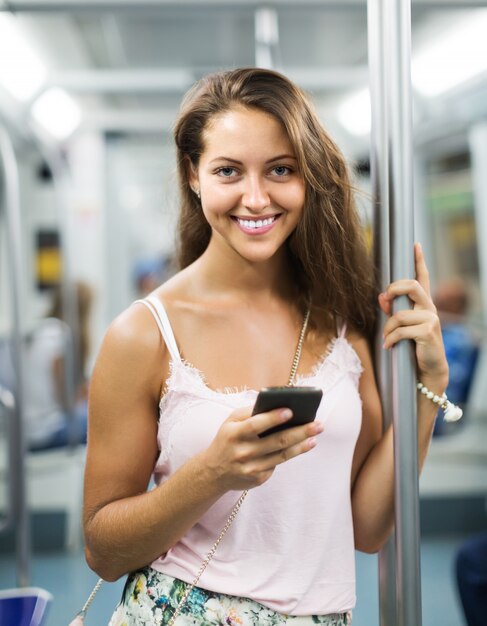 Mujer que usa el teléfono inteligente en el metro