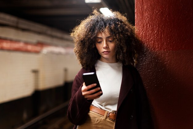 Mujer que usa un teléfono inteligente mientras viaja con el metro en la ciudad