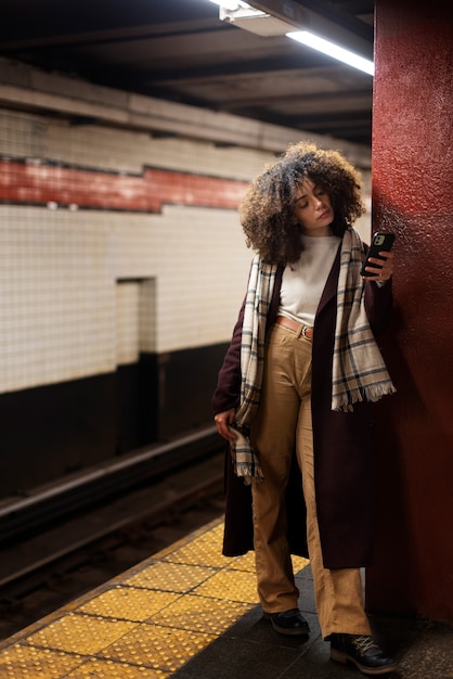 Mujer que usa un teléfono inteligente mientras viaja con el metro en la ciudad