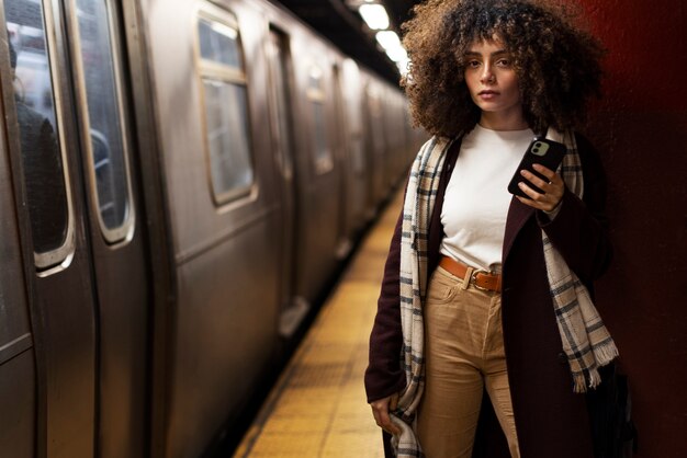 Mujer que usa un teléfono inteligente mientras viaja con el metro en la ciudad