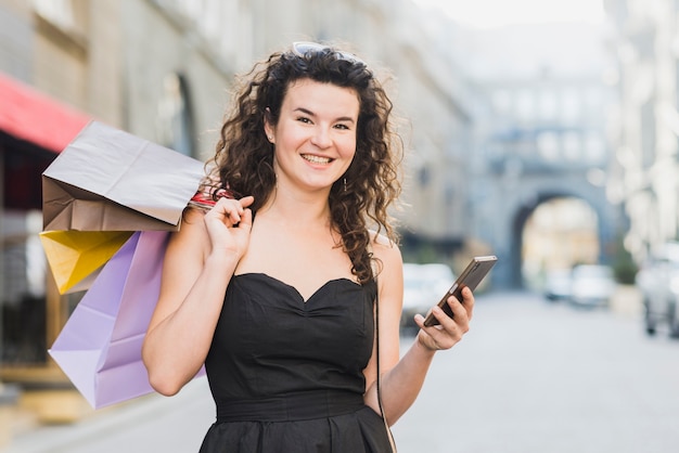 Foto gratuita mujer que usa el teléfono móvil mientras que hace compras en la calle