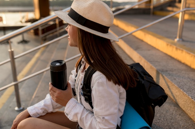 Mujer que viaja con mochila con termo