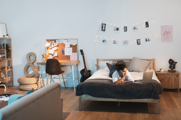 Mujer quedándose en la cama y mirando en la computadora portátil