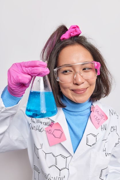 mujer química investiga la propiedad de la materia mezcla reactivos sostiene cristalería inventa y desarrolla nuevos medicamentos y productos hace observaciones vestida con bata médica guantes de goma