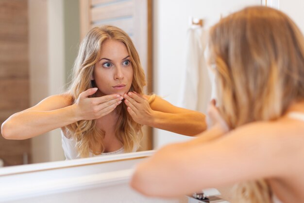 Mujer quitando la espinilla de su rostro