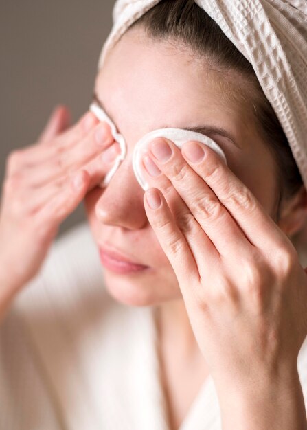 Mujer quitando sombra de ojos con agua micelar