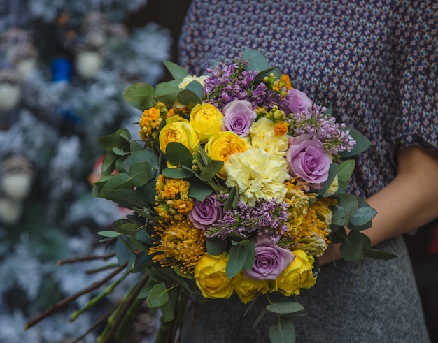 Una mujer con un ramo de flores de color otoño otoño en la mano