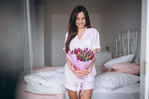 Mujer con ramo de flores en dormitorio