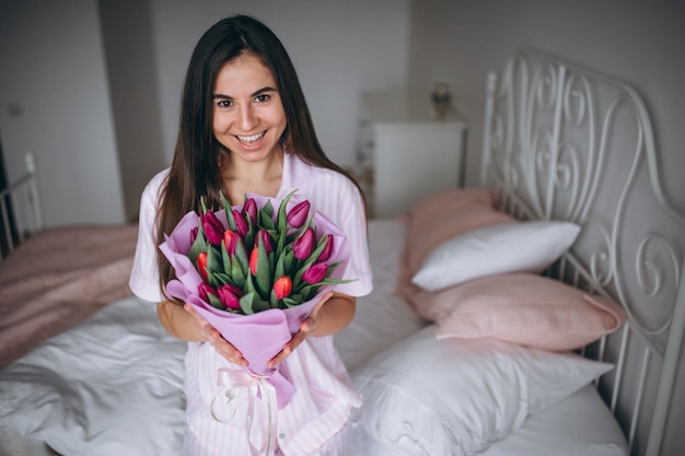 Mujer con ramo de flores en dormitorio