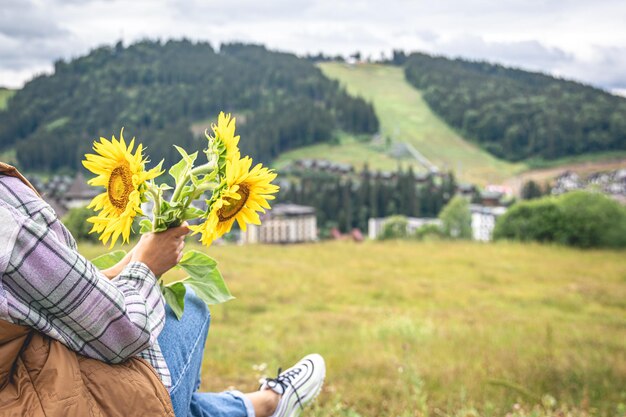 Mujer con un ramo de girasoles en la naturaleza en una zona montañosa