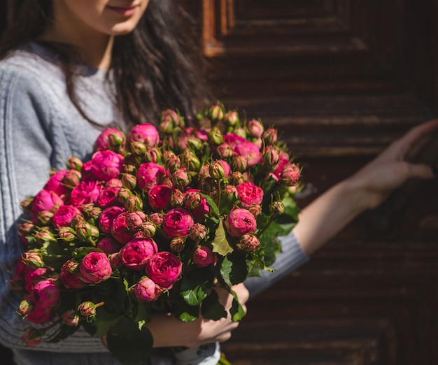 Una mujer con un ramo de peonías rosas en la mano