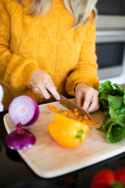 Mujer rebanar pimiento y cocinar en una cocina