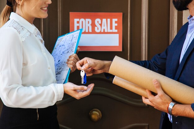 Mujer recibiendo llave de agente inmobiliario