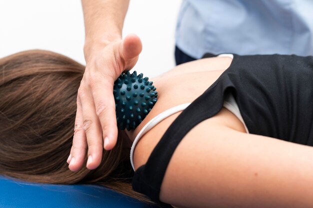 Mujer recibiendo masaje de fisioterapeuta con bola en el cuello