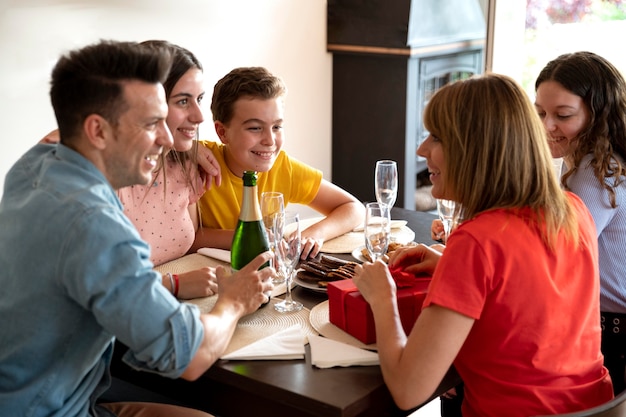 Mujer recibiendo regalo en la cena rodeada de familia