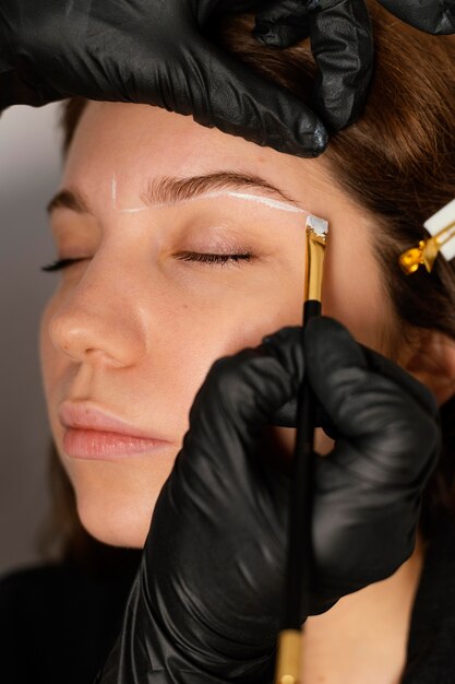 Mujer recibiendo un tratamiento de cejas de esteticista