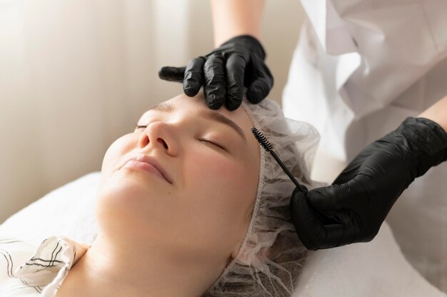 Mujer recibiendo un tratamiento de cejas en el salón de belleza