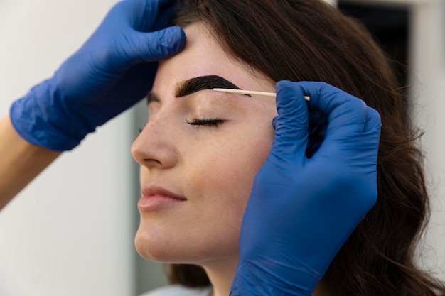 Mujer recibiendo un tratamiento de cejas en un salón de belleza