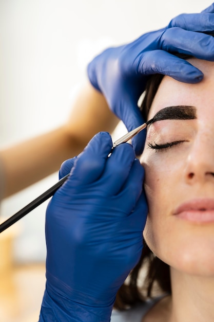 Mujer recibiendo un tratamiento de cejas en un salón de belleza