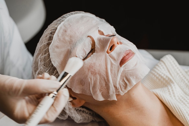 Mujer recibiendo un tratamiento con mascarilla para la piel en el centro de bienestar