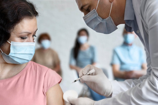 Foto gratuita mujer recibiendo vacuna inyectada por médico masculino