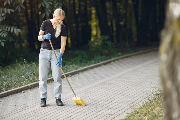 Mujer recoge hojas y limpia el parque.