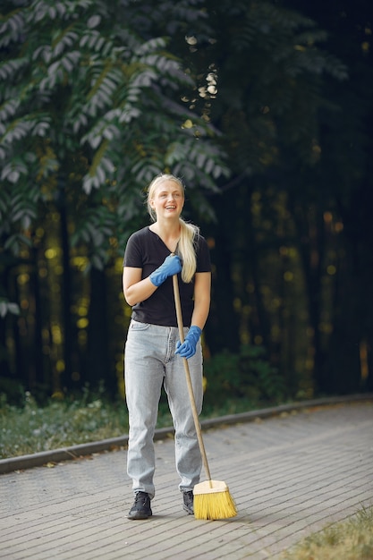 Mujer recoge hojas y limpia el parque.