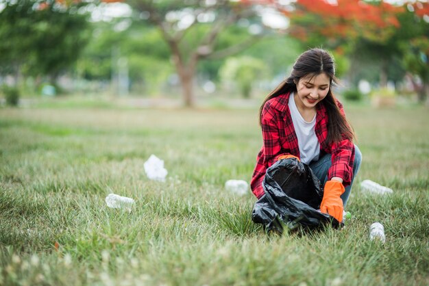 Mujer recogiendo basura en una bolsa negra.