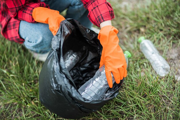 Mujer recogiendo basura en una bolsa negra.