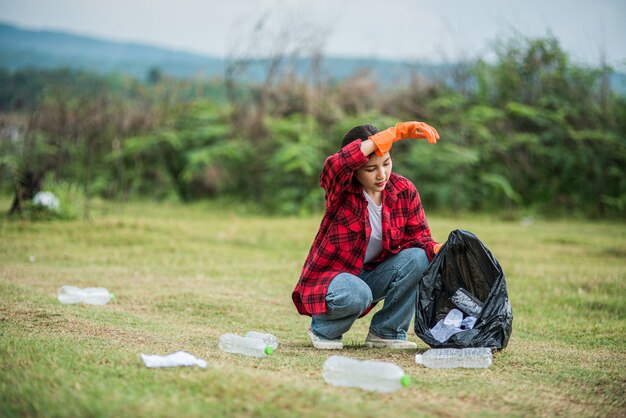 Mujer recogiendo basura en una bolsa negra.