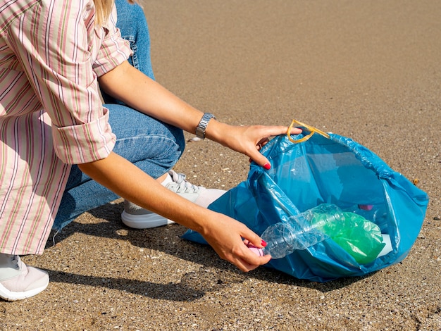 Mujer recogiendo botellas de plástico en bolsa