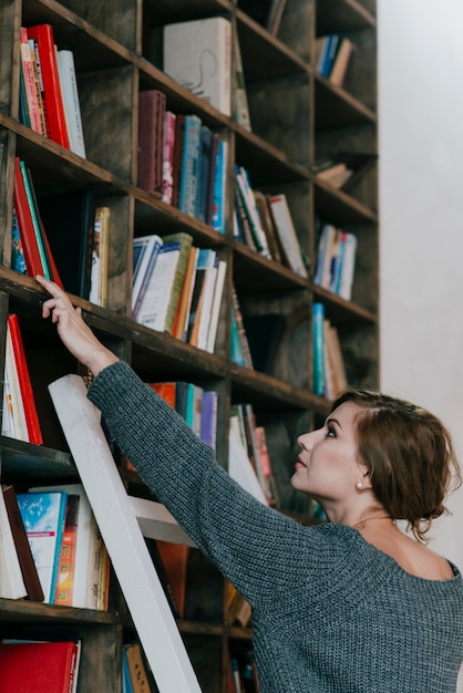 Foto gratuita mujer recogiendo libros de estantería