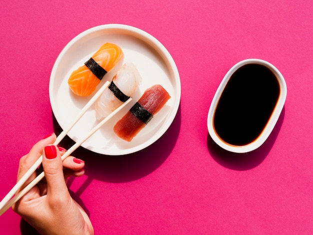 Mujer recogiendo un sushi del plato con palitos