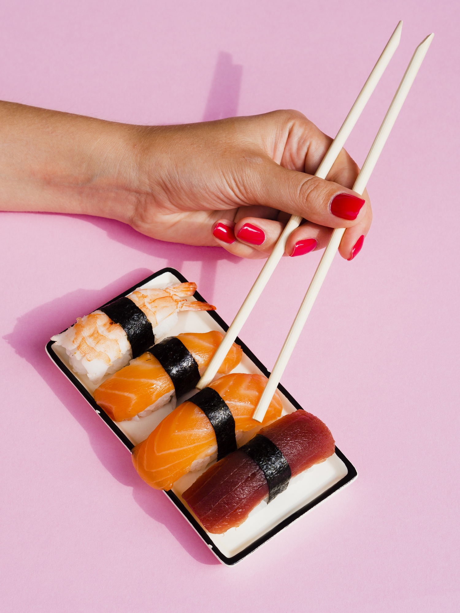 Mujer recogiendo un sushi de salmón del plato