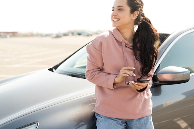 Mujer recostada en el auto al aire libre