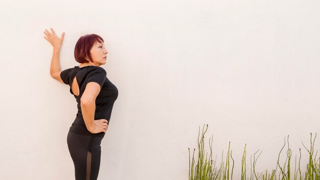 Mujer recostada sobre una pared y estiramiento