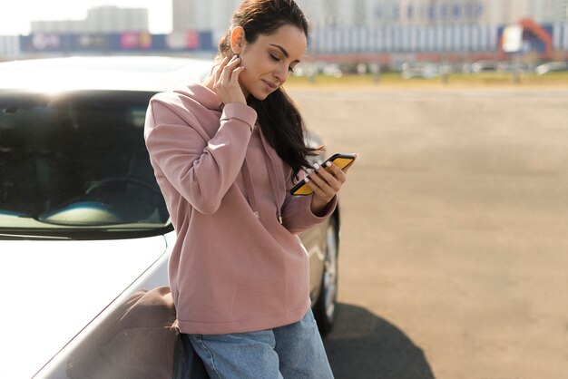 Mujer recostada en su vehículo