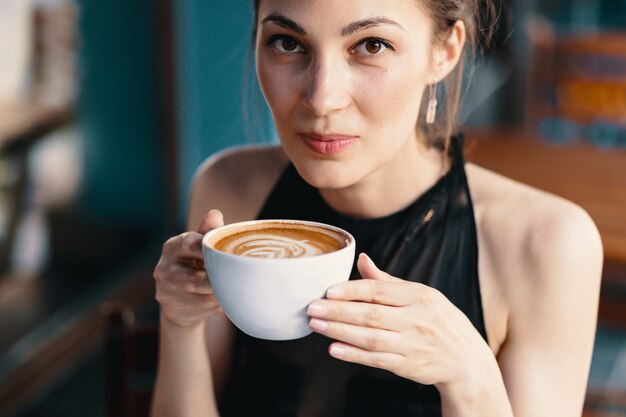 Mujer refinada disfrutando de capuchino o latte en un vibrante colorfu