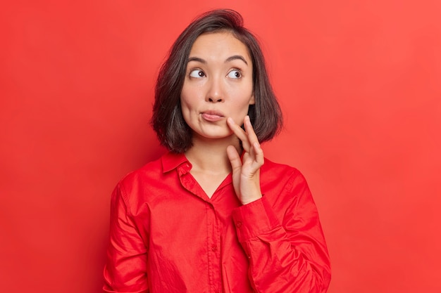 Mujer reflexiona fututre decide qué comprar mientras hace compras aislado en rojo