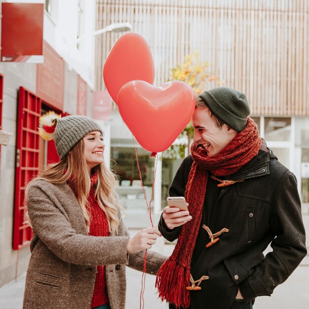 Mujer regalar globos para hombre con teléfono inteligente