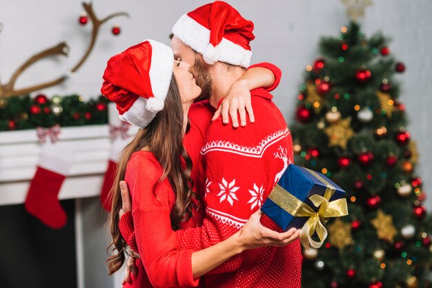 Mujer con regalo abrazando y besando al hombre