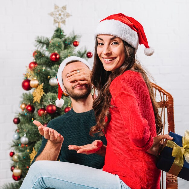 Mujer con regalo cerrando los ojos al hombre.