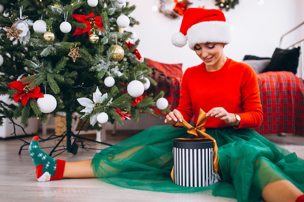 Mujer con regalos por arbol de navidad.