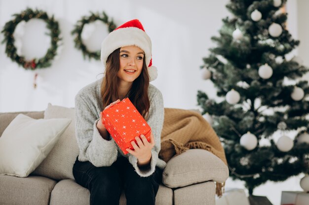 Mujer con regalos por el árbol de navidad