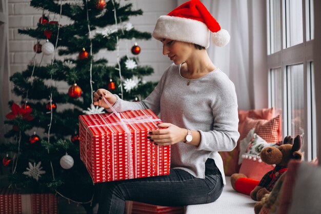 Mujer con regalos de navidad por arbol de navidad