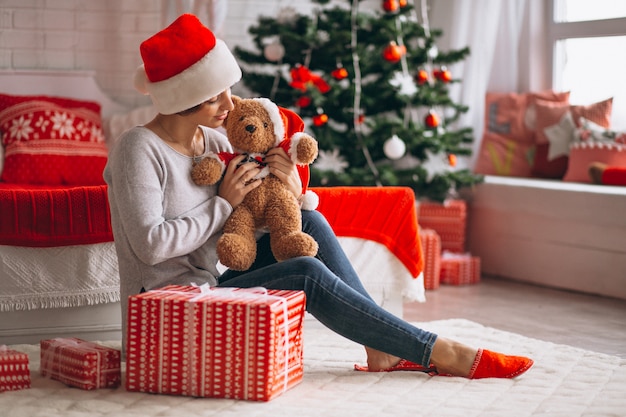 Mujer con regalos de navidad por arbol de navidad